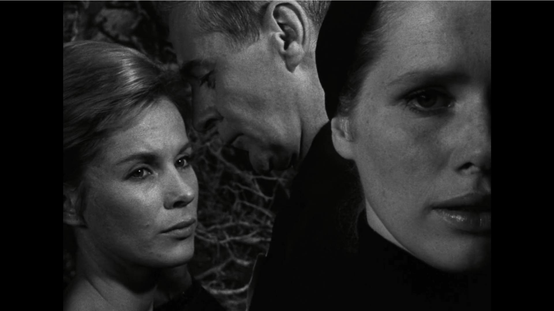 Liv Ullmann as Elisabet is in the foreground looking ahead, while Bibi Andersson as Alma stands behind with Elisabet's husband, looking at Elisabet